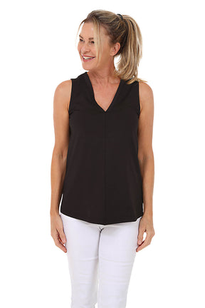 Woman wearing a black sleeveless top and white pants on a white background