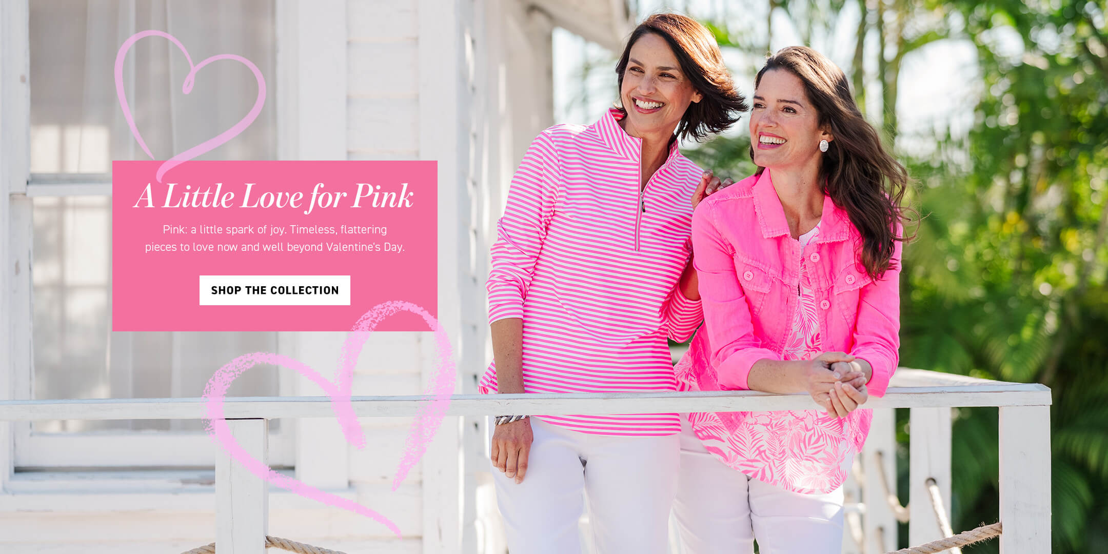 Two women in pink and white outfits standing on a porch with a pink banner above them.