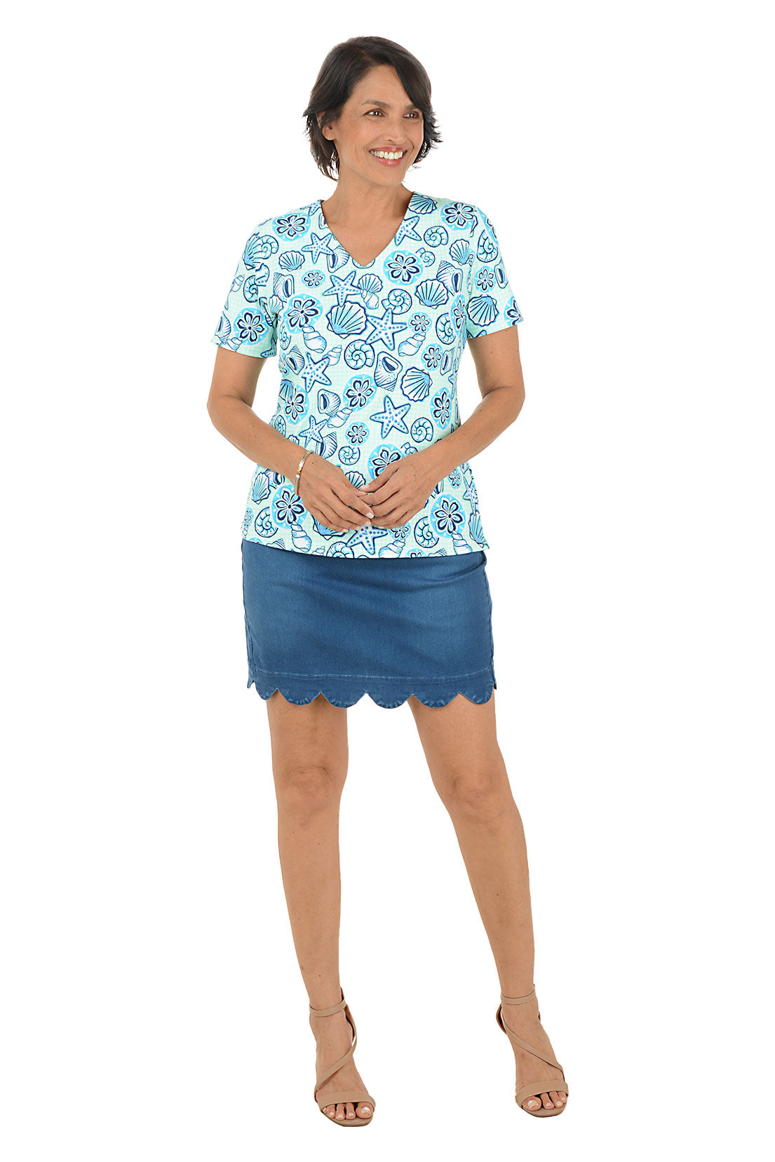 Woman wearing a blue and white patterned top and blue skirt on a white background.