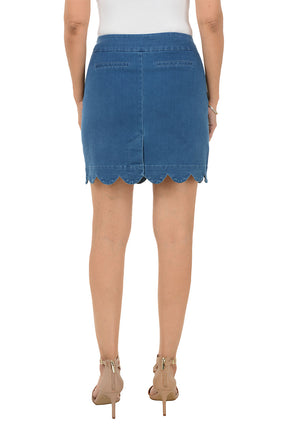 A woman wearing a pull-on denim scalloped hem skort. Back shot.