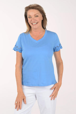 Woman wearing a blue shirt with white pants on a white background
