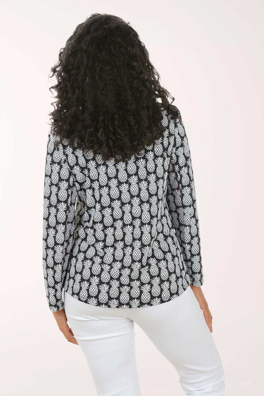 Woman wearing a black and white pineapple patterned top on a white background