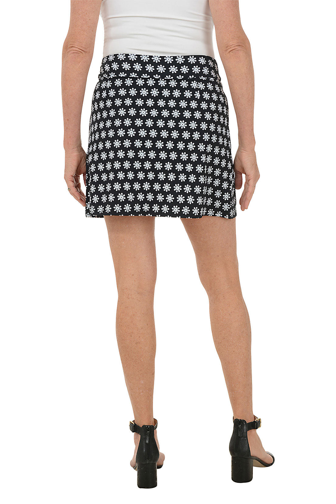 Person wearing a black and white patterned skirt on a white background. Back shot.