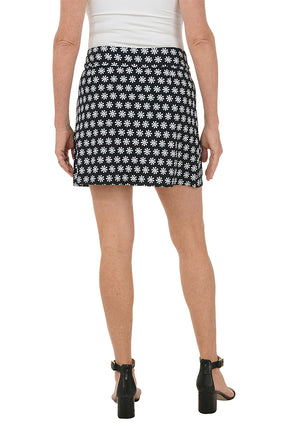 Person wearing a black and white patterned skirt on a white background. Back shot.