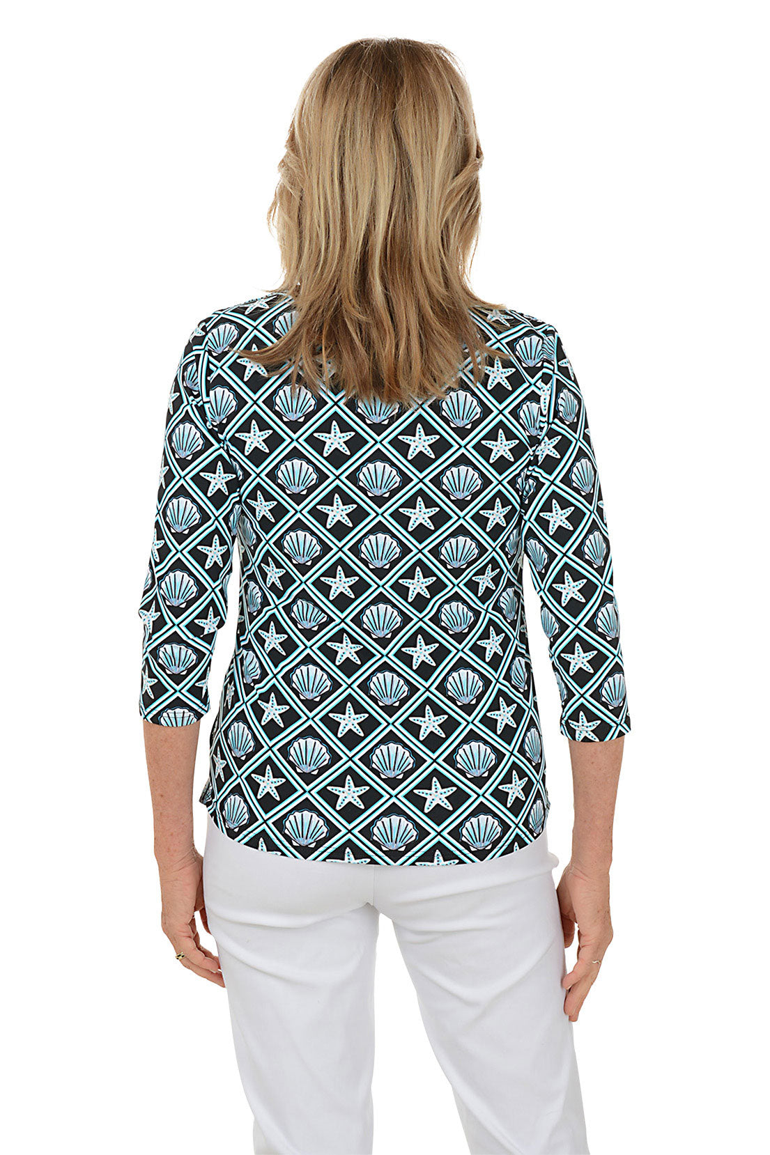 Woman wearing a patterned blouse with white pants on a white background. Back shot.