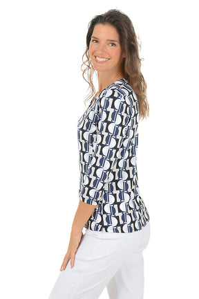 Woman wearing a v-neck 3/4 sleeve half moon geometric patterned blouse in black, tan and blue with a white background. Side shot.