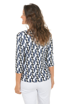 Woman wearing a v-neck 3/4 sleeve half moon geometric patterned blouse in black, tan and blue with a white background. Back shot.