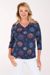 Woman wearing a navy 3/4 sleeve top with a firework print