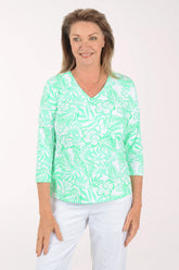 Woman wearing a green and white patterned top on a white background