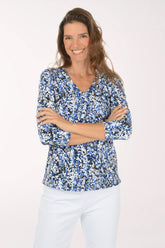 Front view of a woman with her arms crossed in the Anthony's Resort Wear Growing Vines UPF50+ V-Neck Top, a cobalt, black and white leafy vine print with 3/4 sleeves.