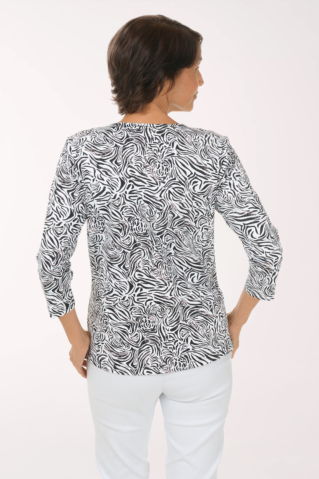 Back view of the Silver Zebra Swirl UPF50+ V-Neck Top showing the black and white swirl print and hip-length straight hem over white pants.