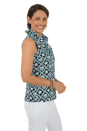 Woman wearing a sleeveless top with shell pattern and white pants on a white background