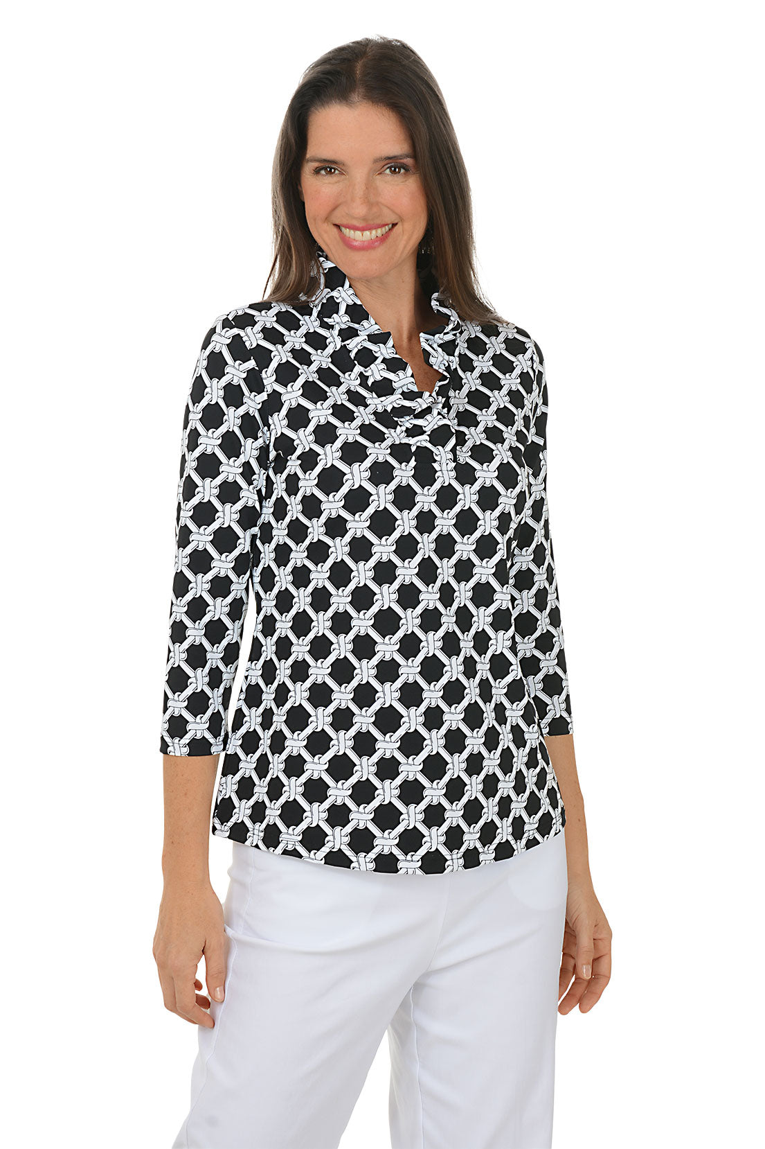 Woman wearing a black and white patterned blouse with white pants on a white background.