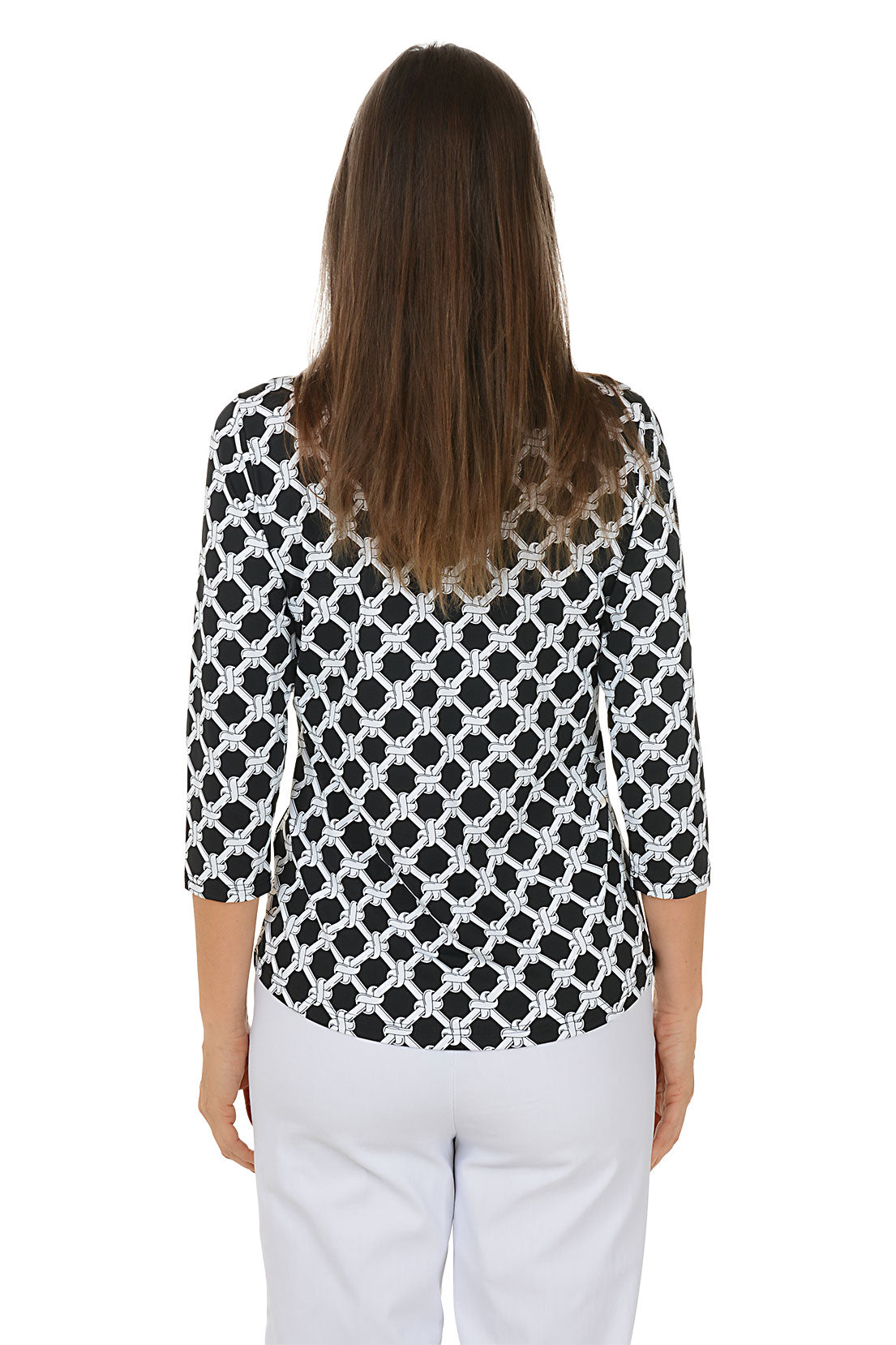 Woman wearing a black and white patterned blouse with white pants on a white background. Back shot.