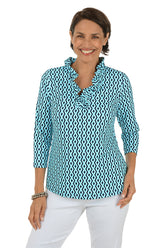 Woman wearing a blue and white patterned shirt with white pants on a white background.