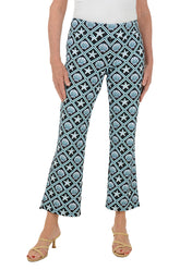 Woman wearing patterned seashell pants with a white top on a white background.