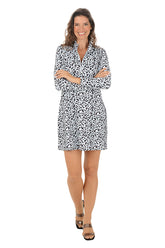 A woman wearing a long sleeve dress with a white leopard pattern and half-zip placket  detail along the neckline.