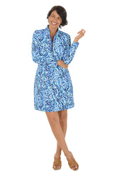 A woman wearing a long sleeve dress with a blue vine pattern and half-zip placket  detail along the neckline.