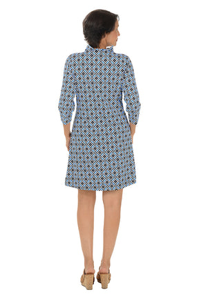 Woman wearing a 3/4 sleeve blue patterned dress on a white background. Back shot.
