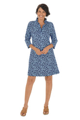 A woman wearing a 3/4 sleeve periwinkle and navy dress with a ruffle neckline.