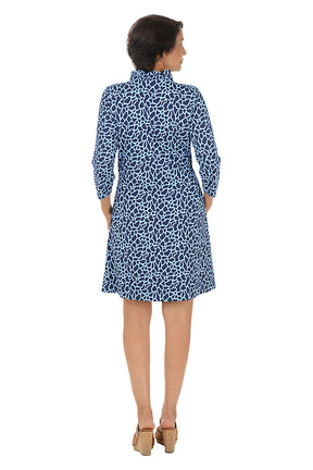 A woman wearing a 3/4 sleeve periwinkle and navy dress with a ruffle neckline. Back shot.