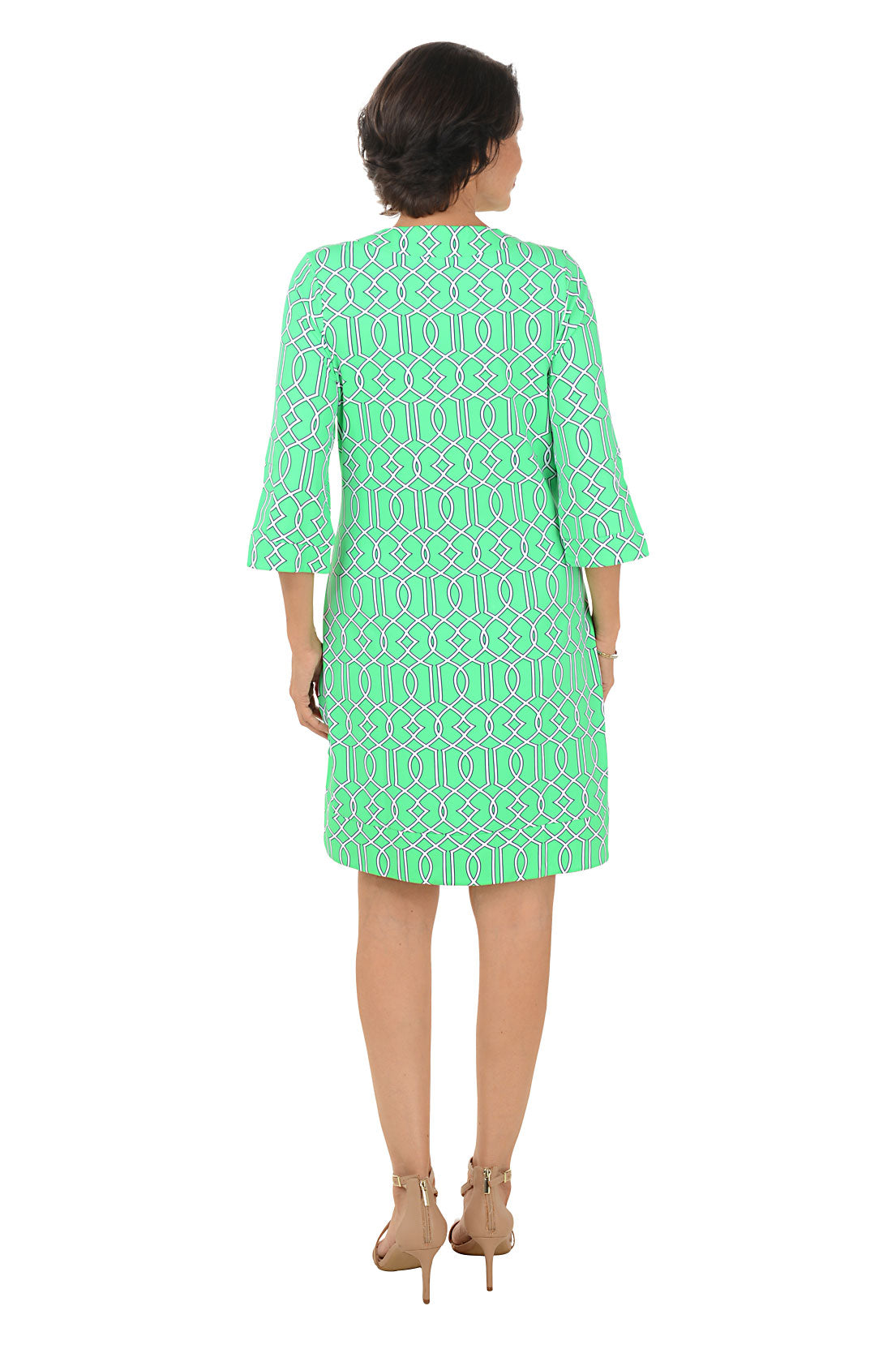 Woman wearing a green patterned dress on a white background. Back shot.