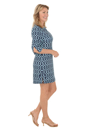 Woman wearing a blue patterned dress on a white background. Side shot.