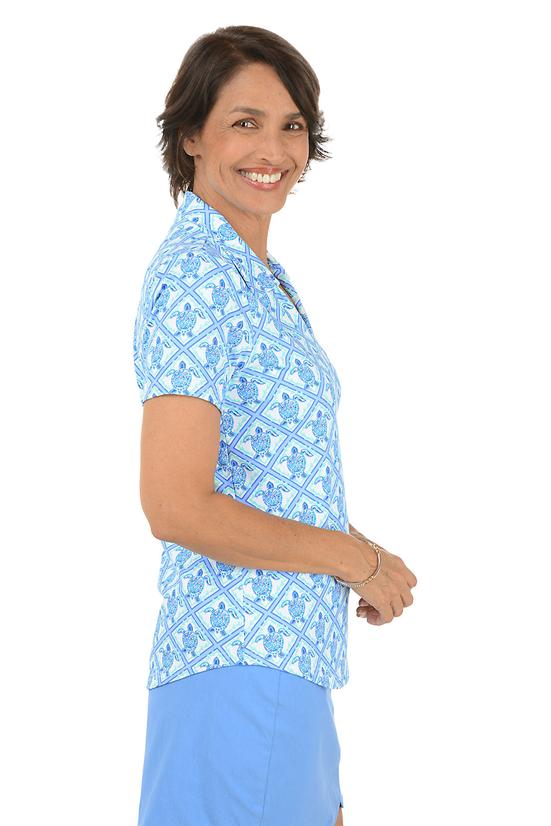 Woman wearing a blue patterned top and skirt on a white background. Side shot.