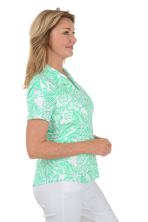 Woman wearing a green floral patterned blouse on a white background. Side shot.