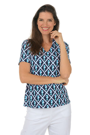 Woman wearing a blue and white patterned top with seahorses on a white background.
