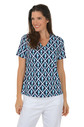 Woman wearing a blue and white patterned top with seahorses on a white background. Second front shot.