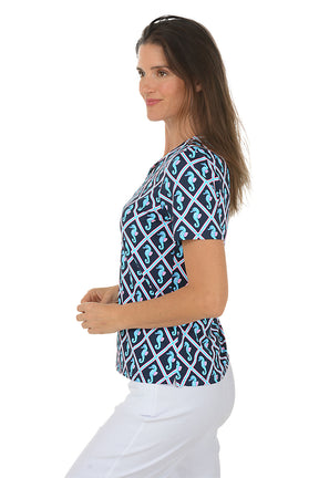 Woman wearing a blue and white patterned top with seahorses on a white background. Side shot.