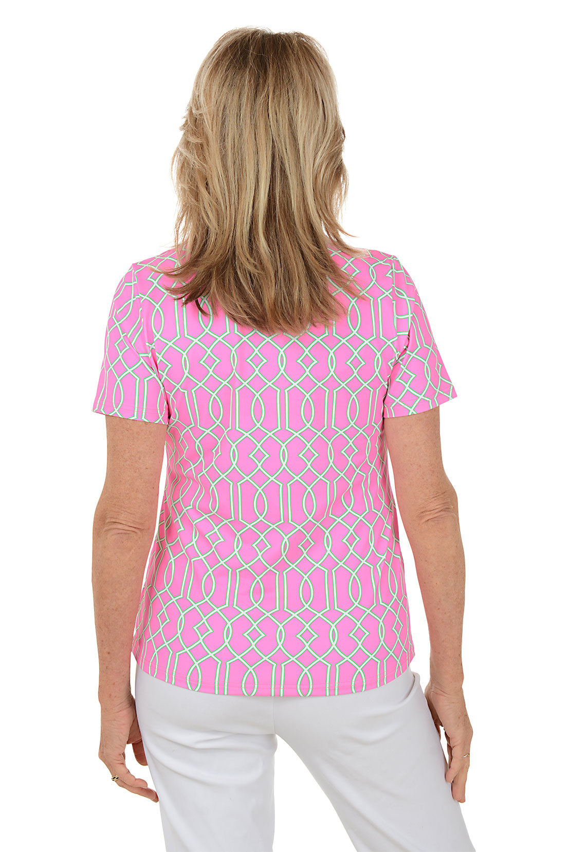 Woman wearing a pink patterned blouse with white pants on a white background. Back shot.