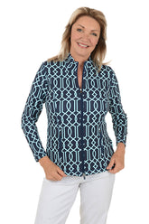 Woman wearing a navy patterned blouse and white pants on a white background