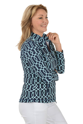 Woman wearing a navy patterned blouse and white pants on a white background