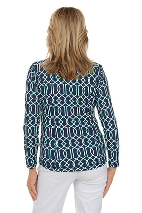 Woman wearing a navy patterned blouse and white pants on a white background