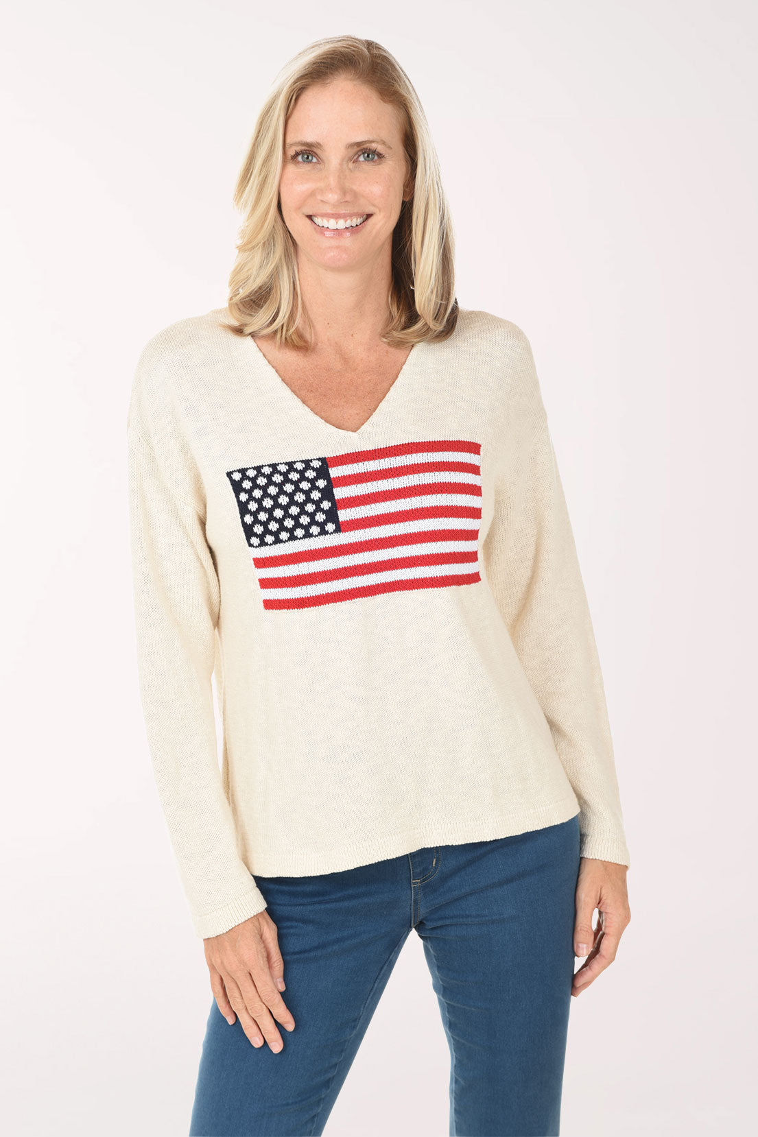 Woman wearing a cream sweater with an American flag design on a white background