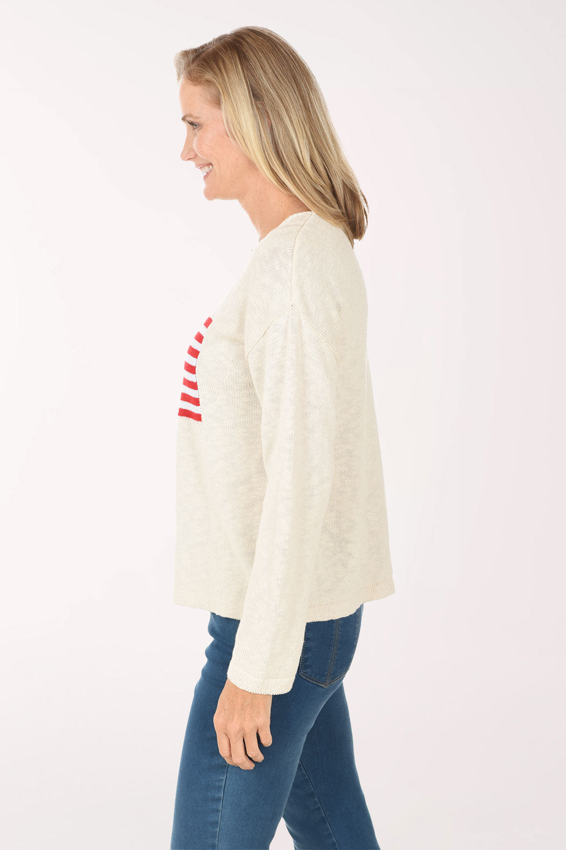 Woman wearing a cream sweater with an American flag design on a white background
