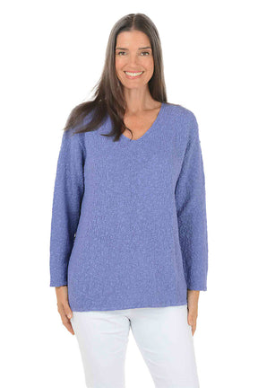 Woman wearing a blue sweater and white pants on a white background