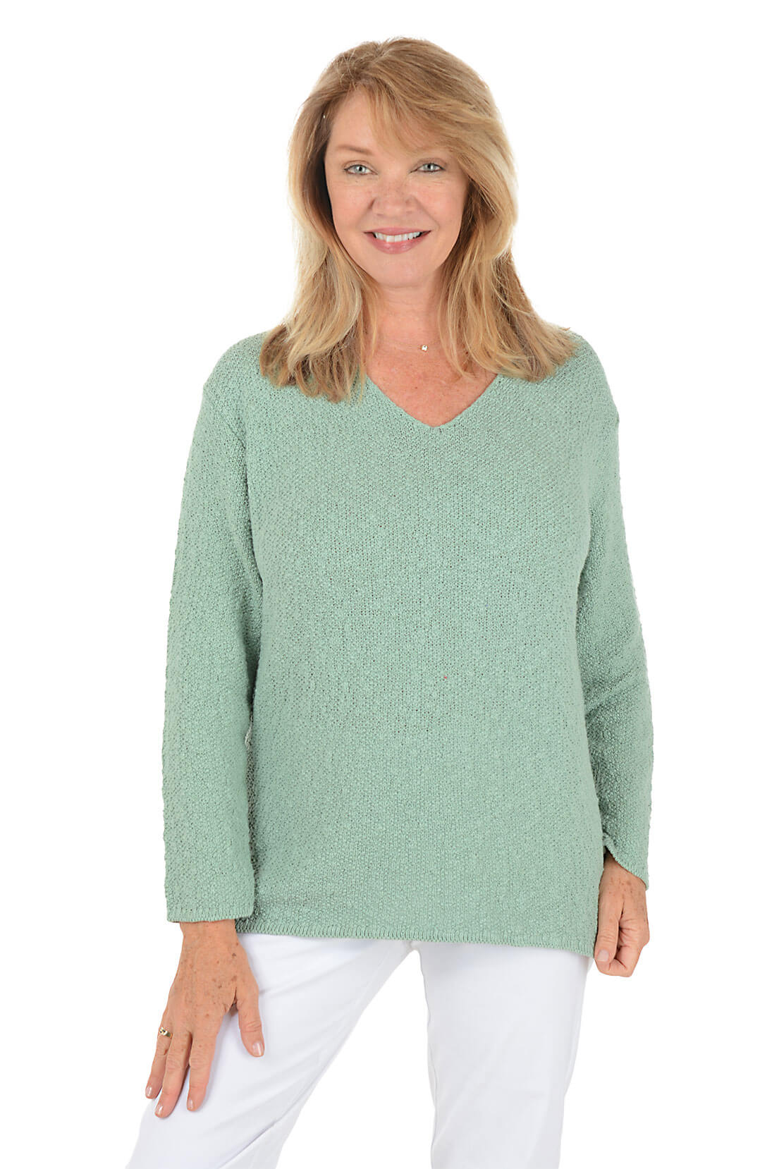 Woman wearing a green sweater and white pants on a white background