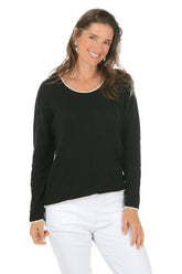 Woman wearing a black long-sleeve top and white pants on a white background