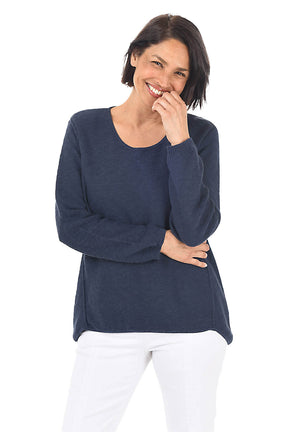 Woman wearing a navy sweater and white pants on a white background