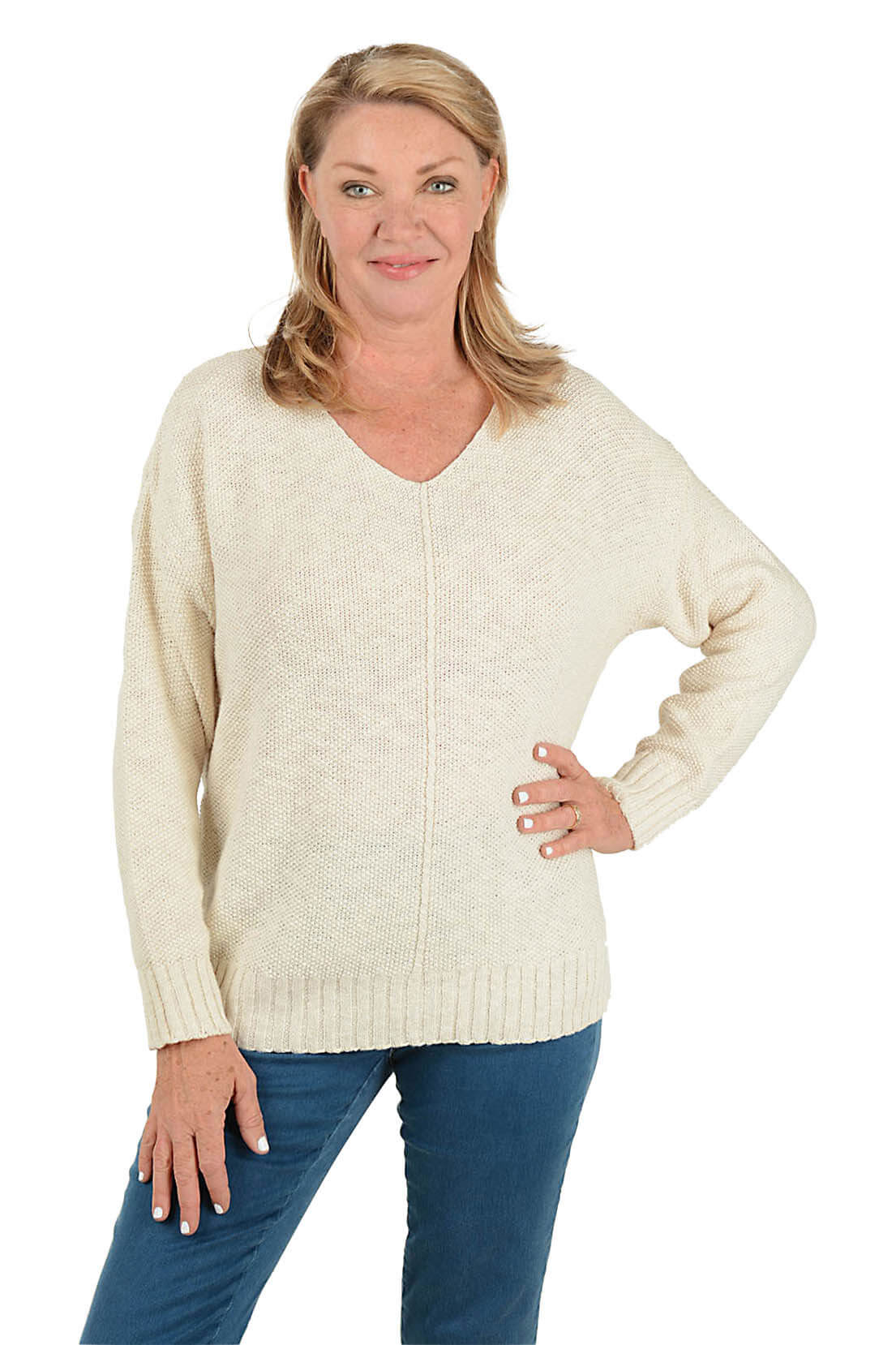 Woman wearing a cream sweater and blue jeans on a white background