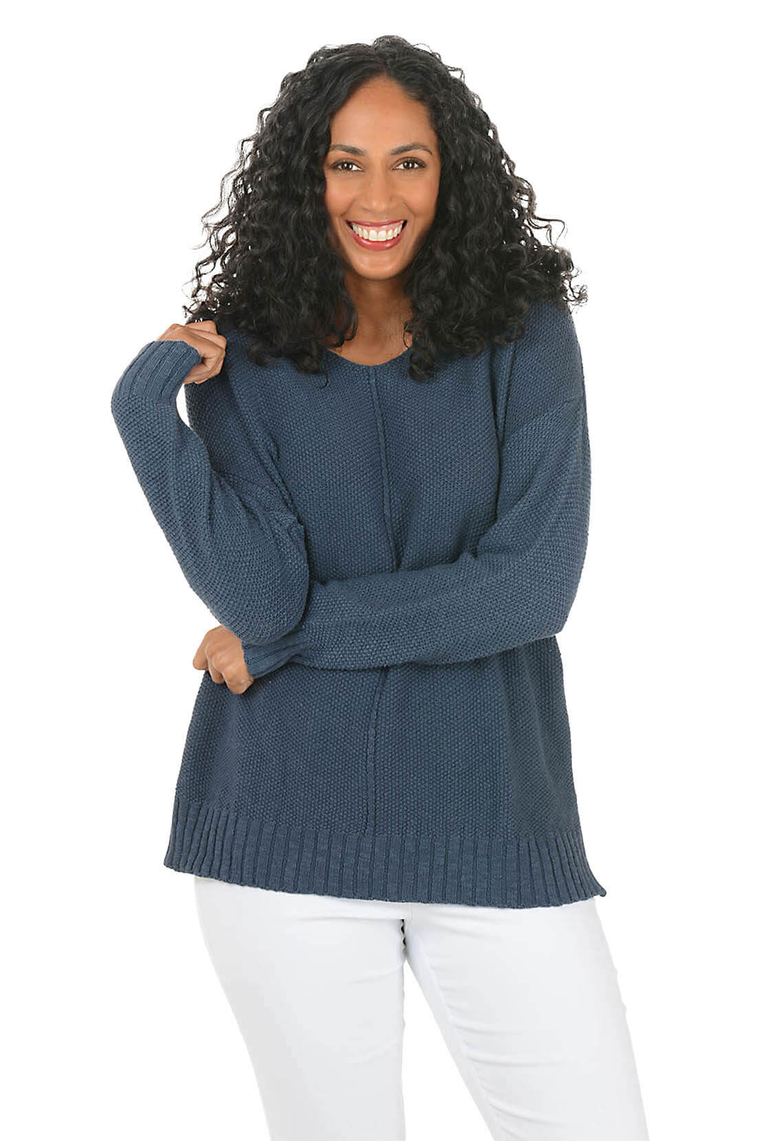 Woman wearing a blue sweater and white pants on a white background