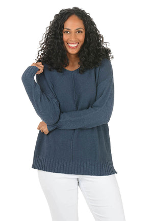 Woman wearing a blue sweater and white pants on a white background
