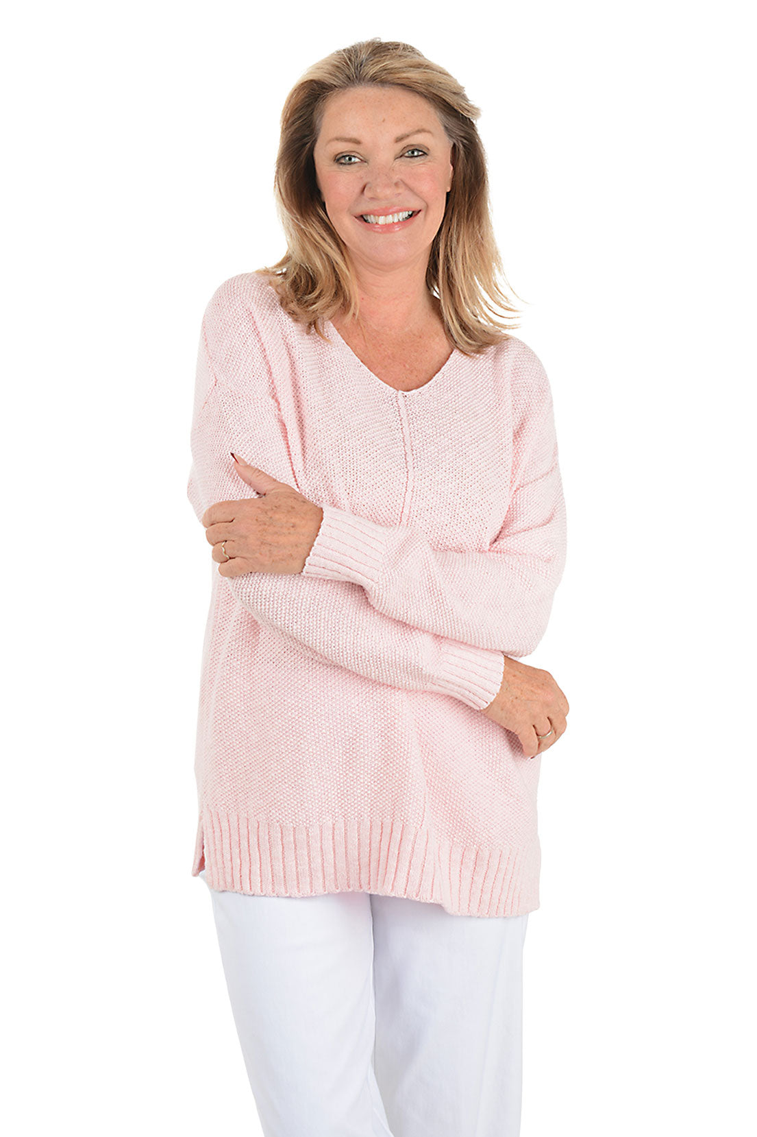 Woman wearing a light pink sweater and white pants on a white background