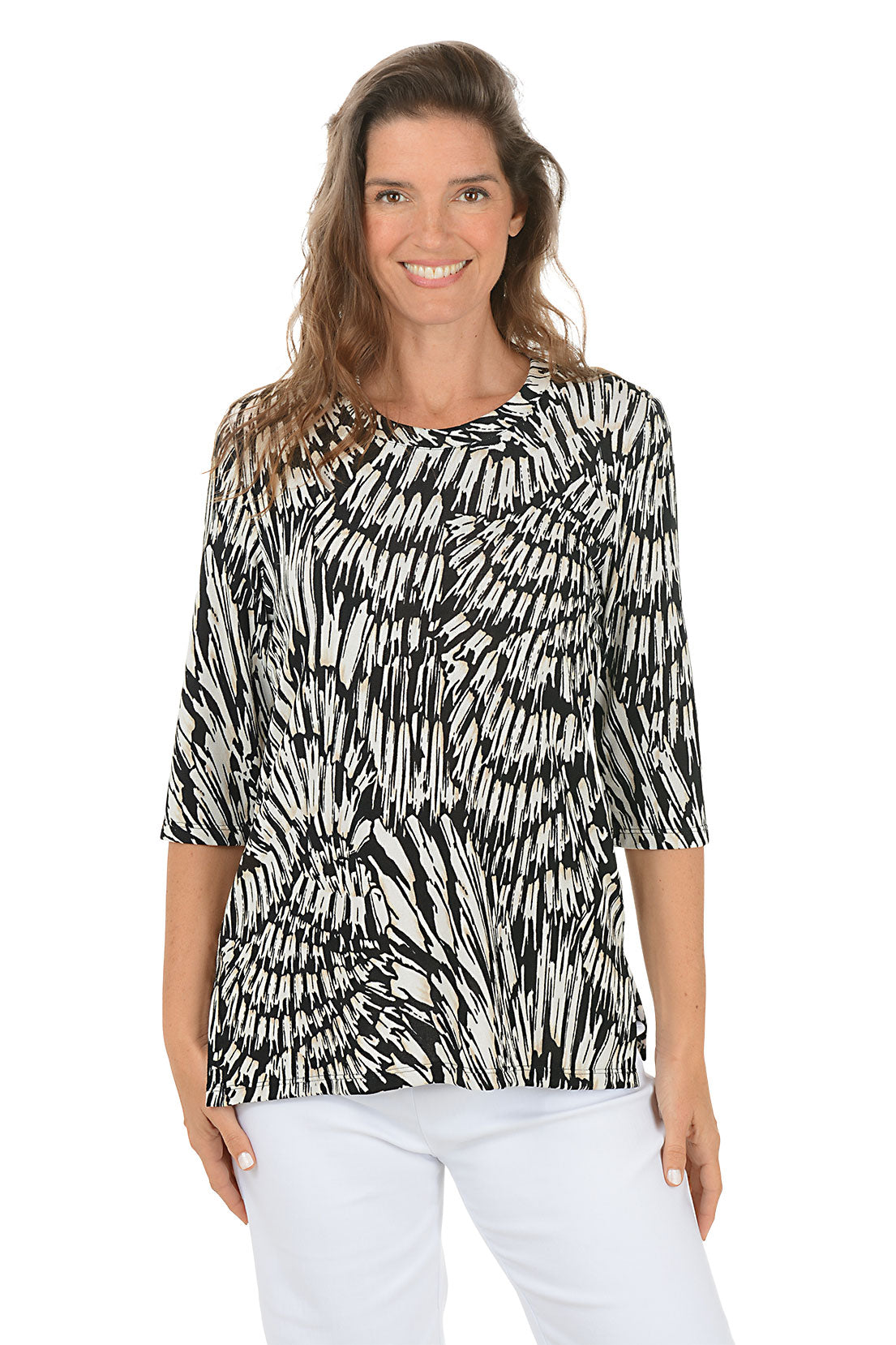 Woman wearing a black and white patterned top with white pants on a white background.