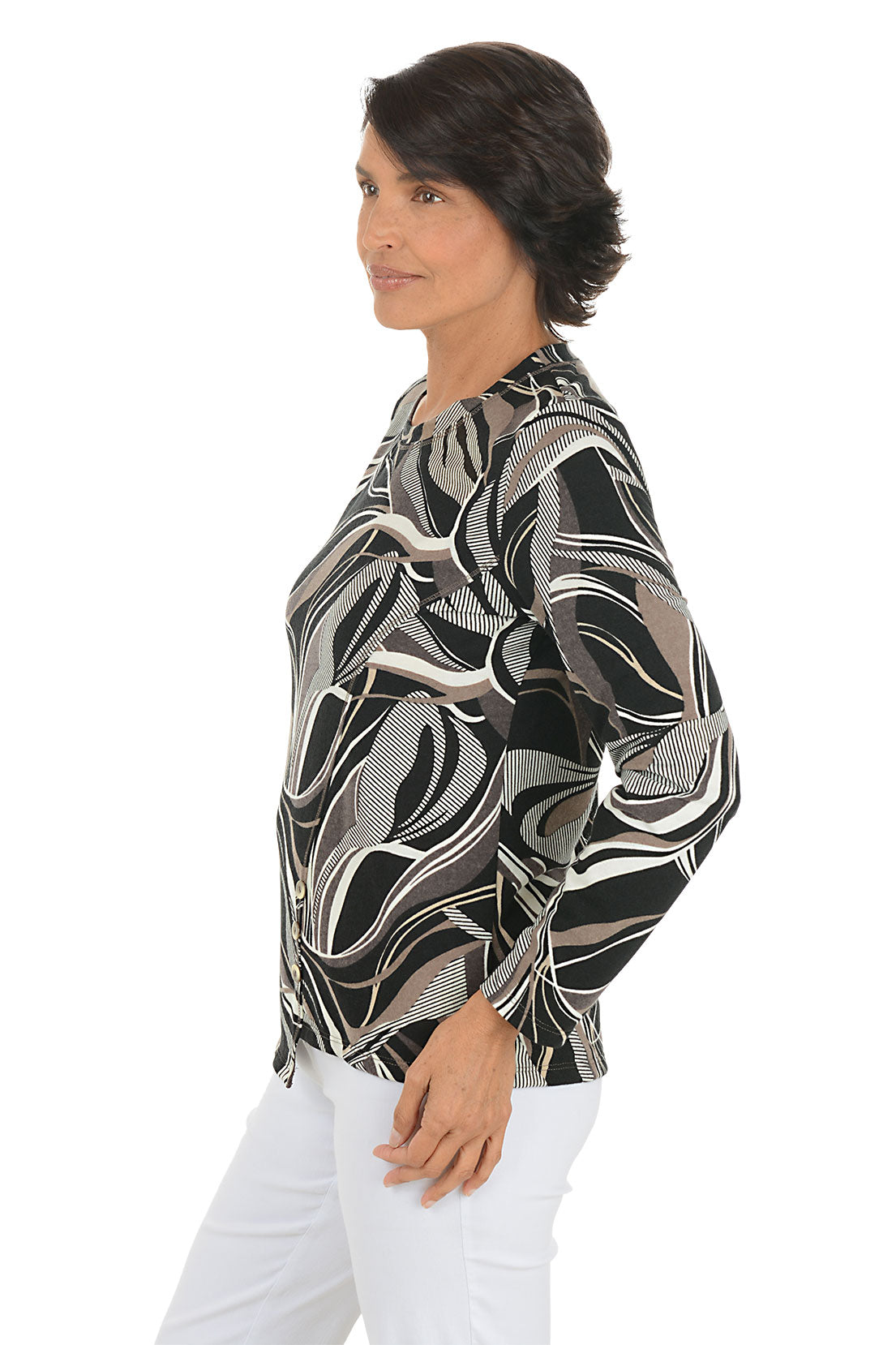 Woman wearing a patterned long-sleeve top and white pants on a white background. Side shot.