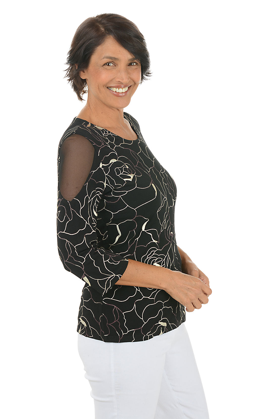 Woman wearing a black floral patterned top on a white background. Side shot.