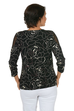Woman wearing a black floral patterned top on a white background. Back shot.